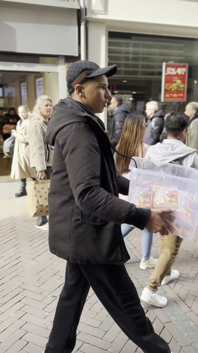 Handing out candy in front of a shop on the Damstraat