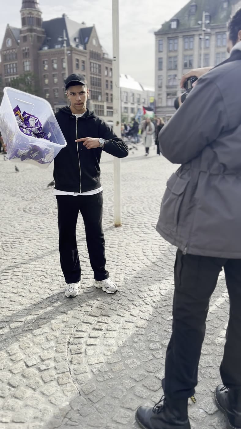 Presenter holding a box of chocolate bars on Dam Square while the camera rolls
