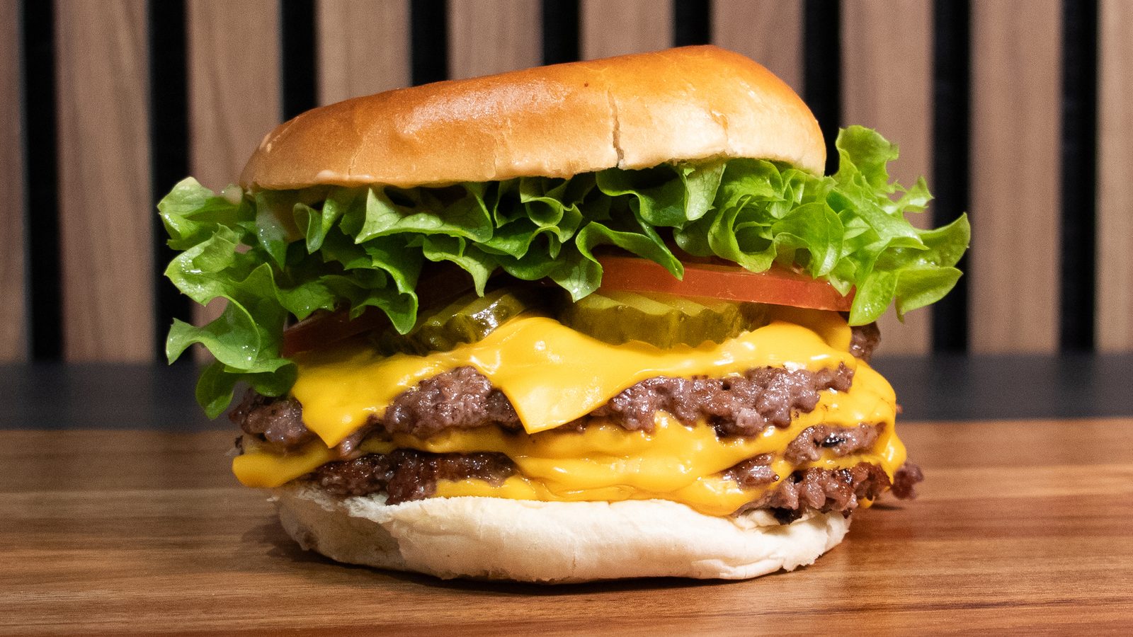 A double cheeseburger with lettuce, pickles and melted cheese