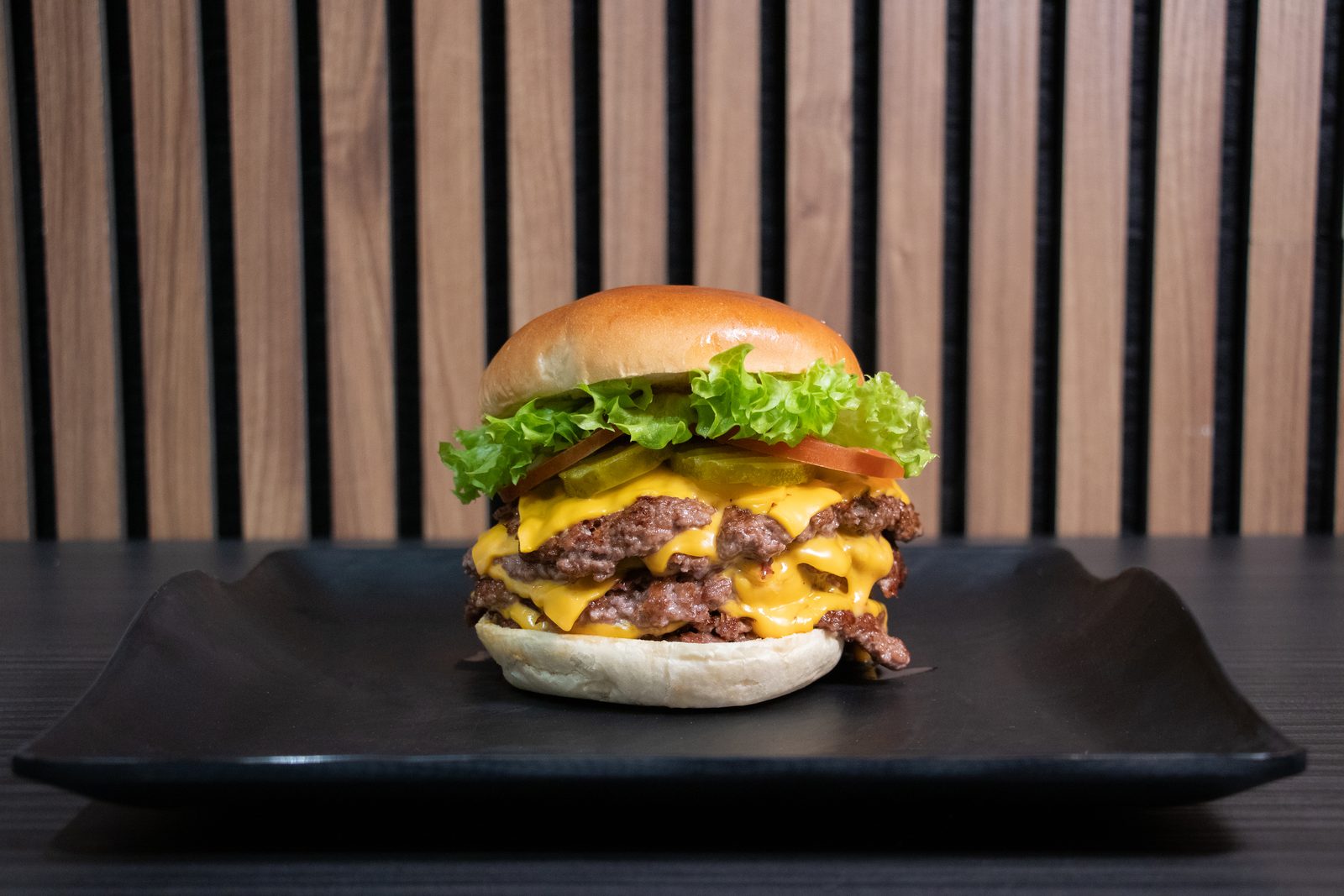A double cheeseburger on a black plate