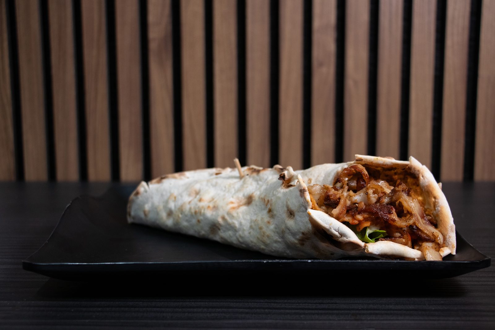 A meat-filled wrap cut open on a black plate