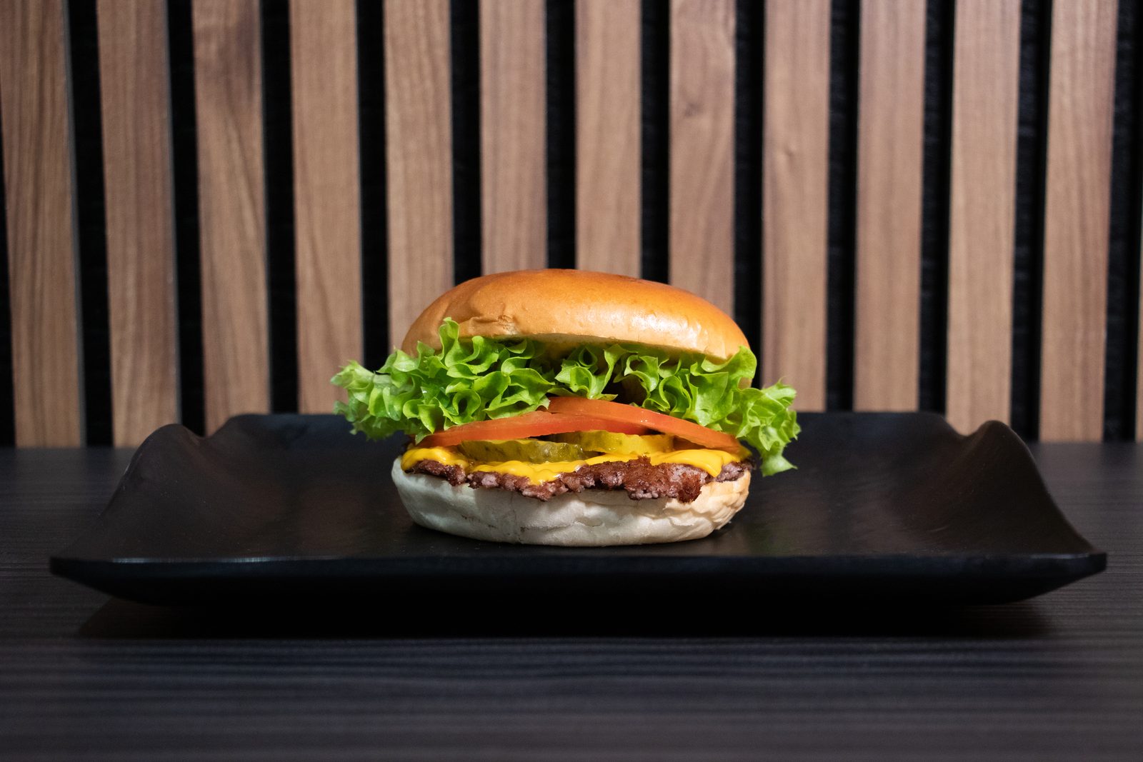 A cheeseburger with lettuce and tomato on a black plate