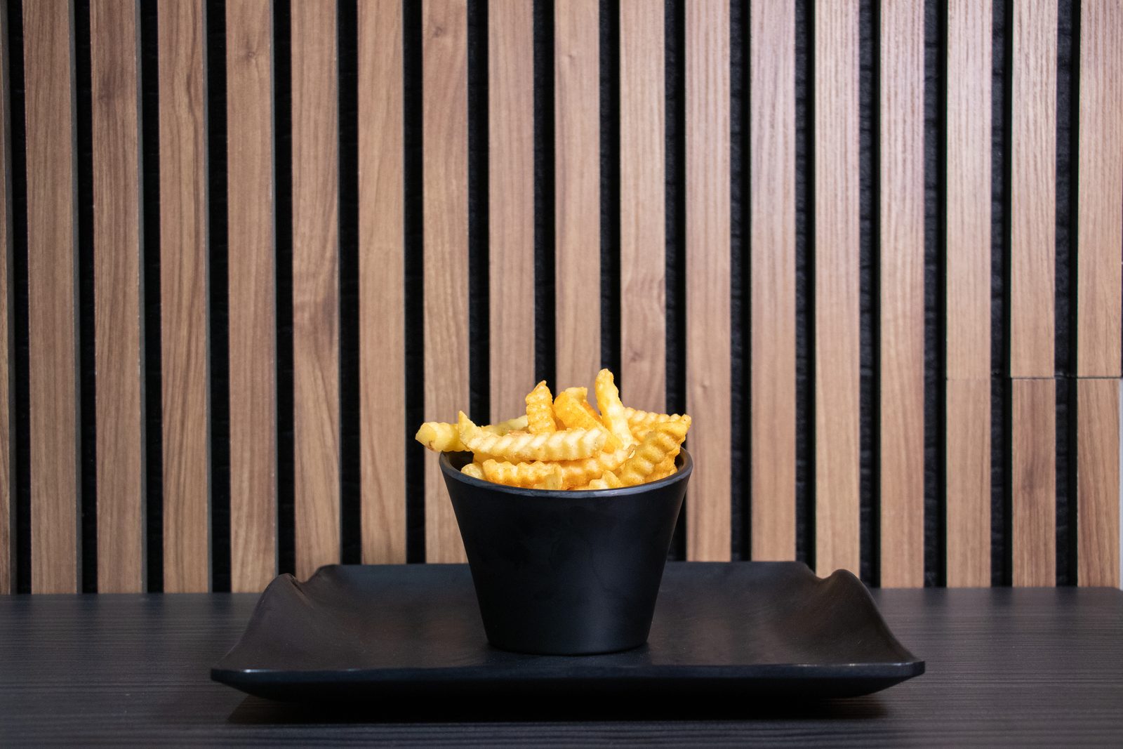 Crinkle fries in a black cup