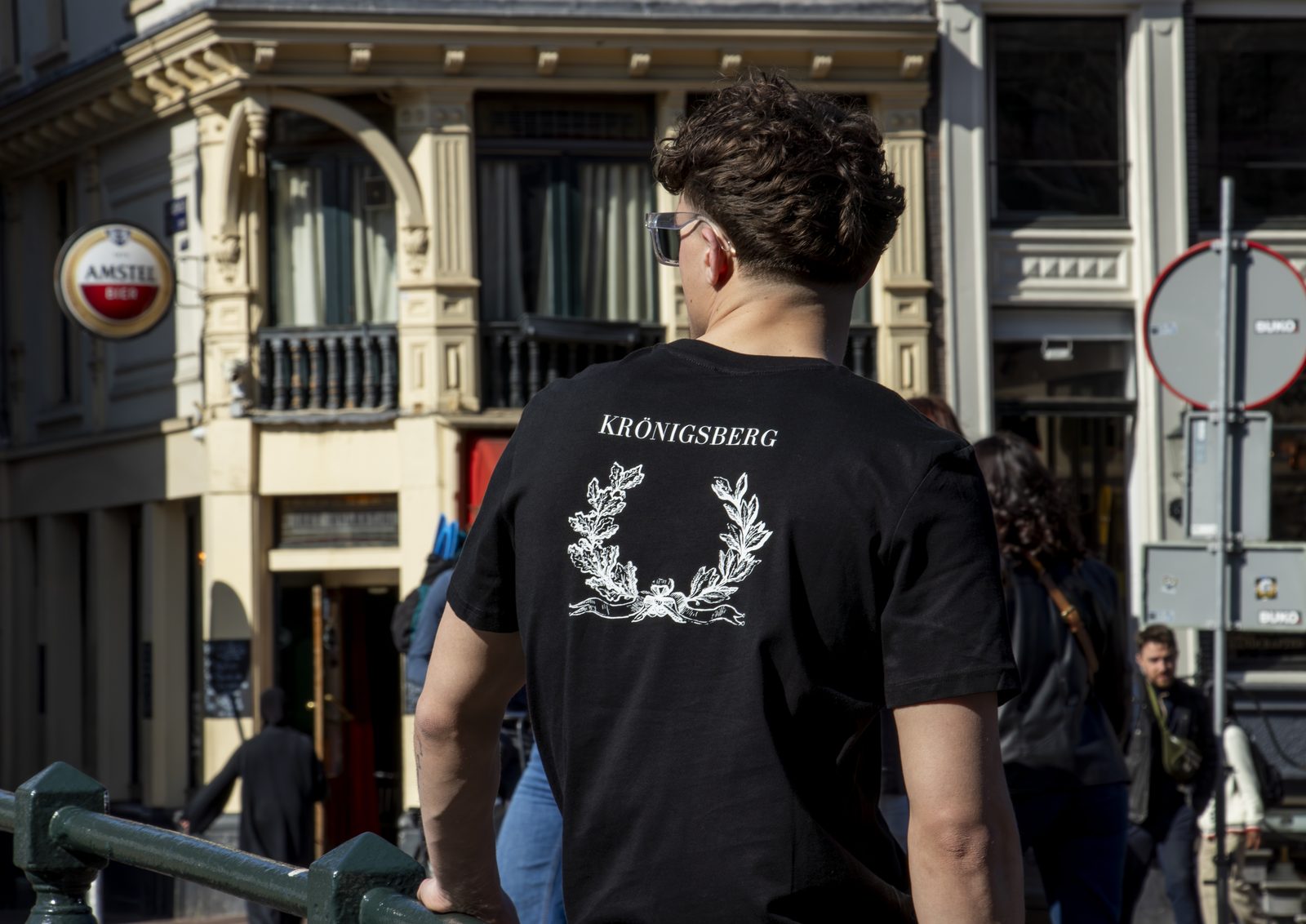 Back of a black Kronigsberg tee with a laurel print in an Amsterdam street