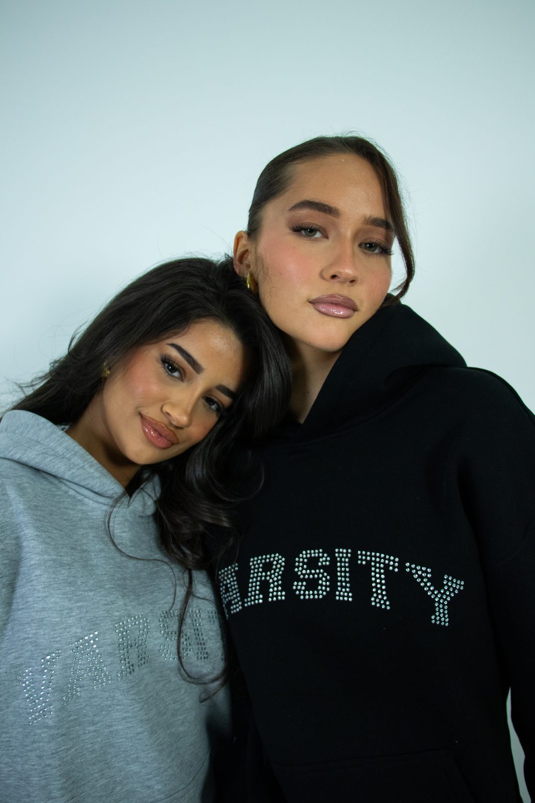 Two models in grey and black Varsity hoodies, close up
