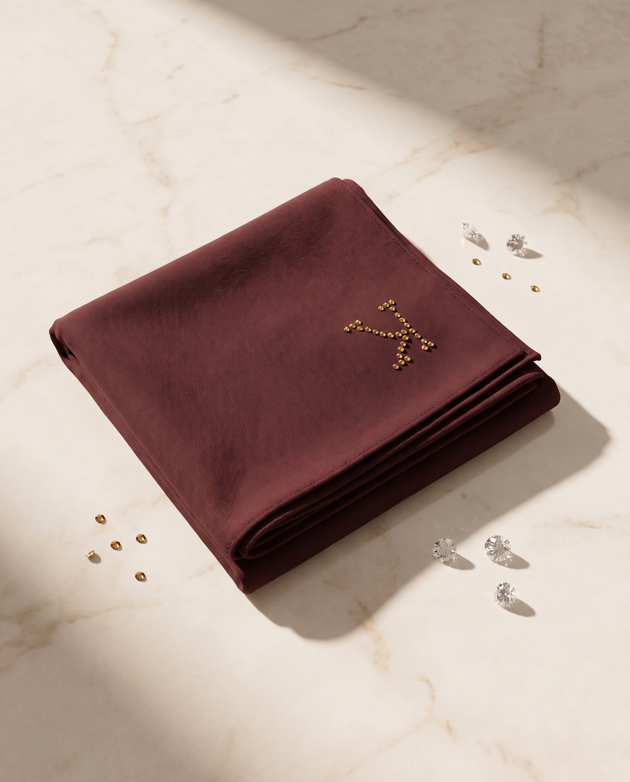 AI image: folded bordeaux hijab with the crystal K on marble