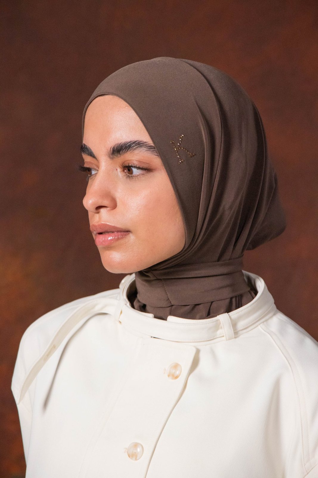 Profile portrait of the model in a brown hijab
