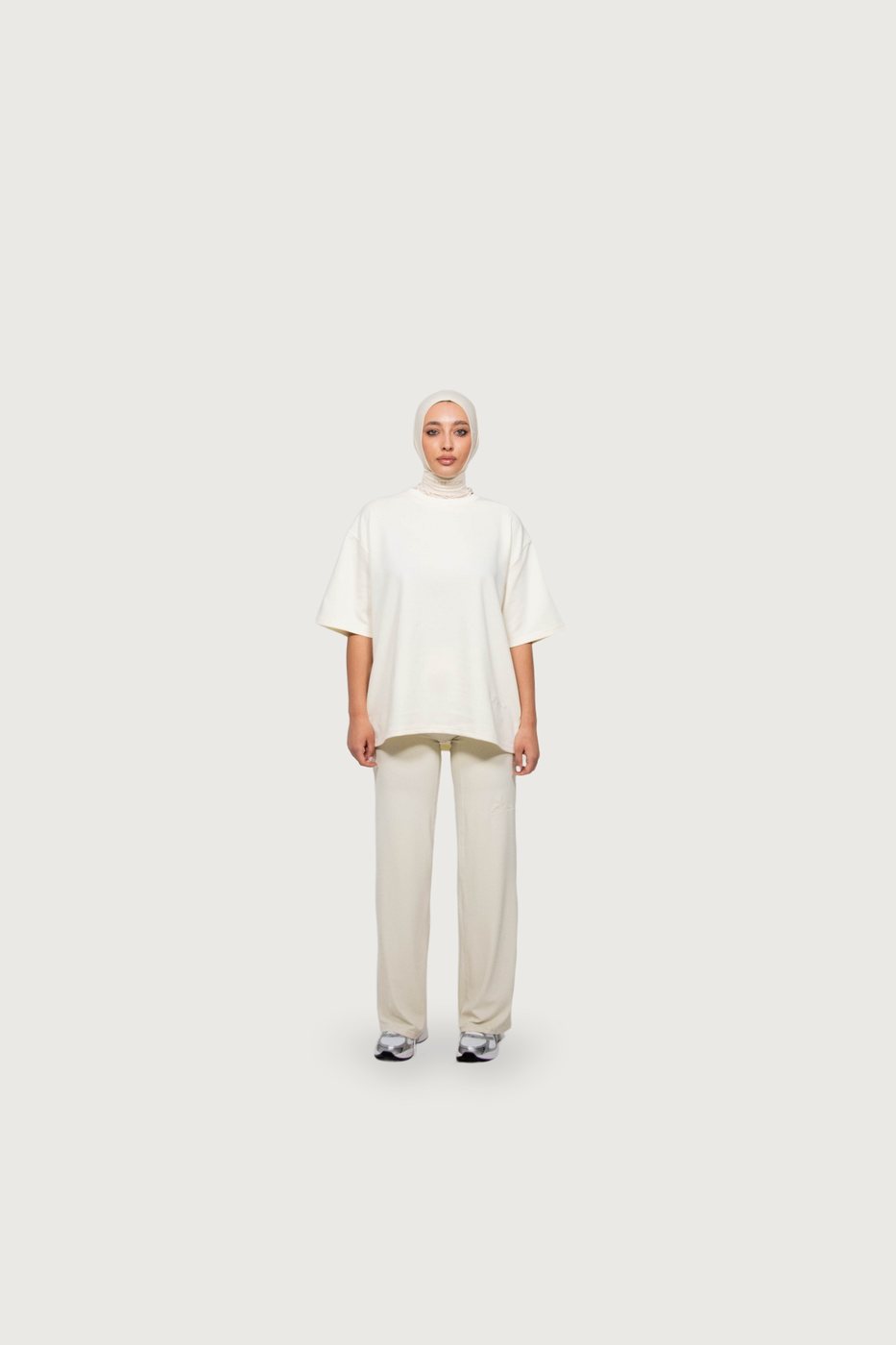 Model in an ivory Signature hijab, ivory oversized tee and wide trousers