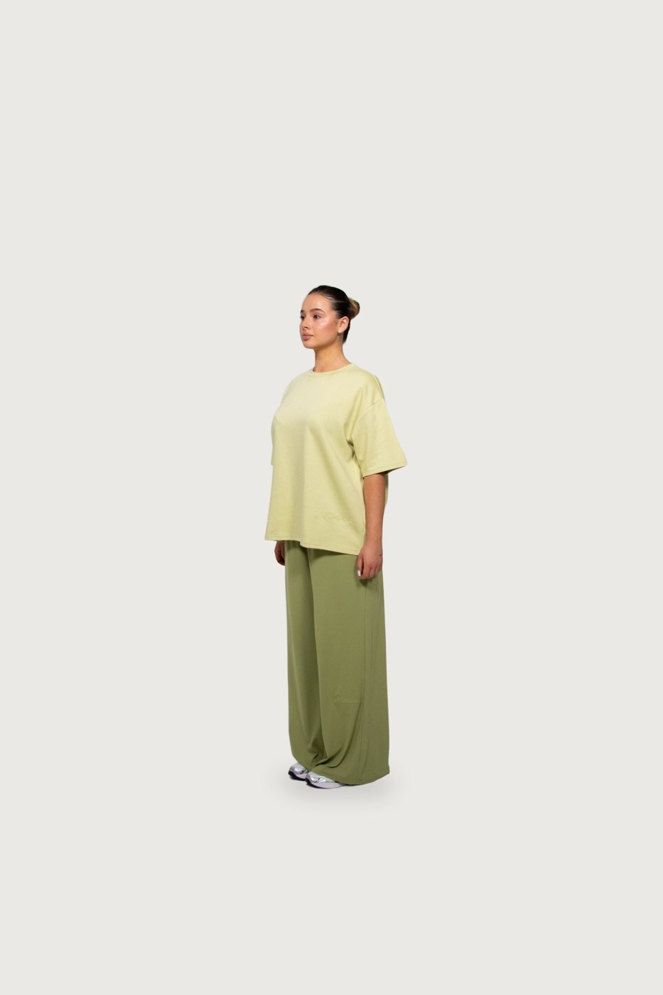 Model in a pale-yellow tee and sage wide-leg trousers, side view