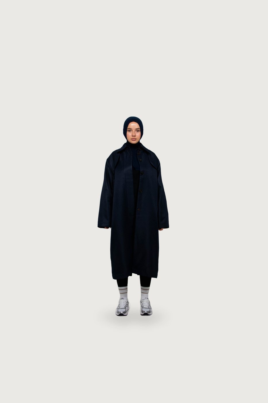 Model in a long navy belted trench coat and navy hijab