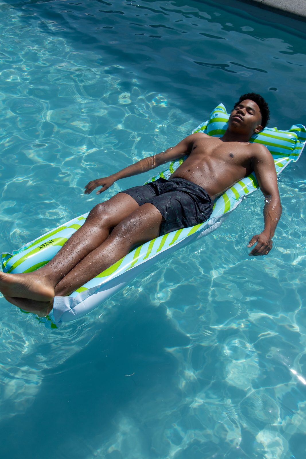 Model floating on a striped lilo in a pool