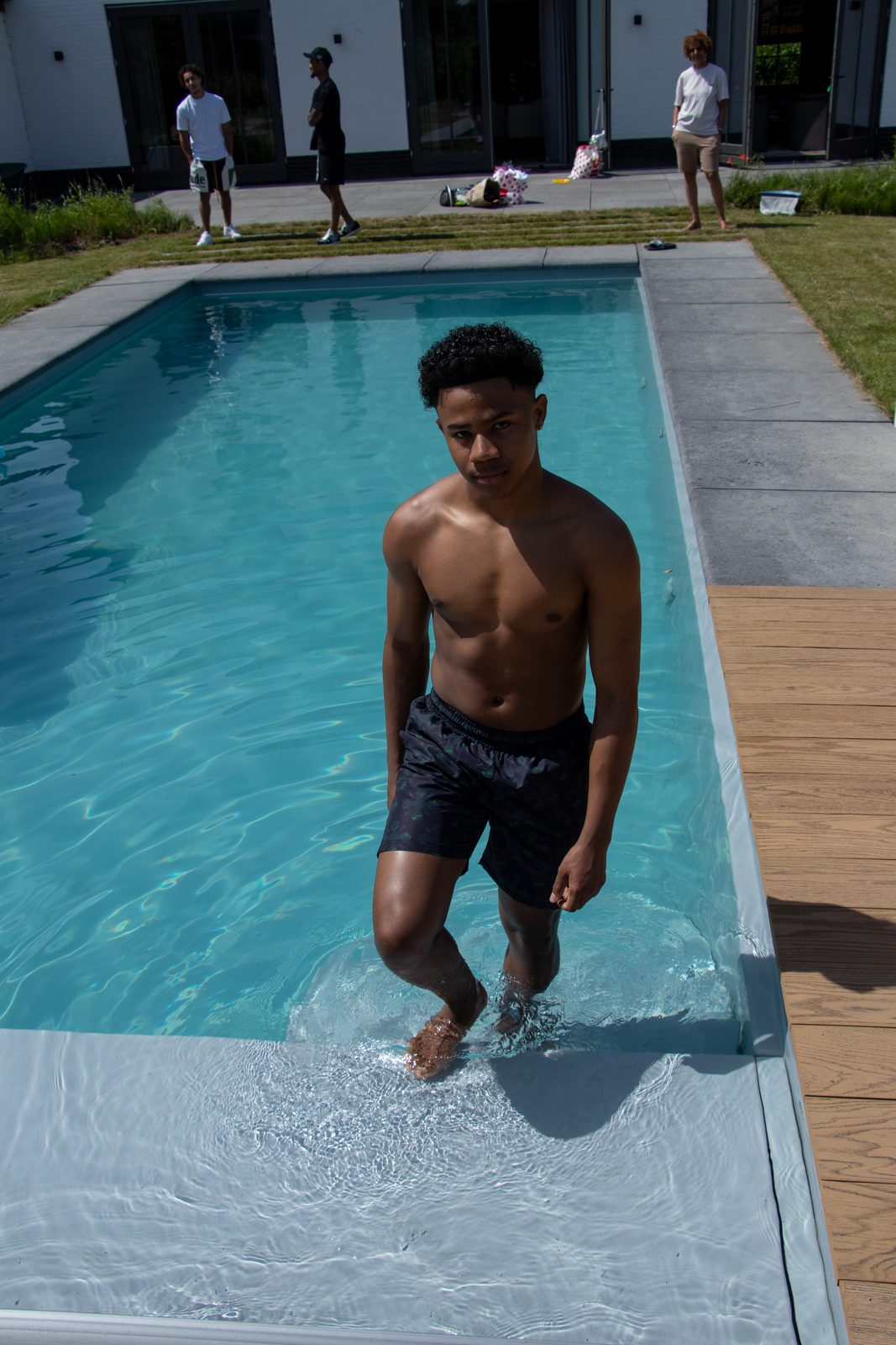 Model stepping into a pool in LMF swim shorts
