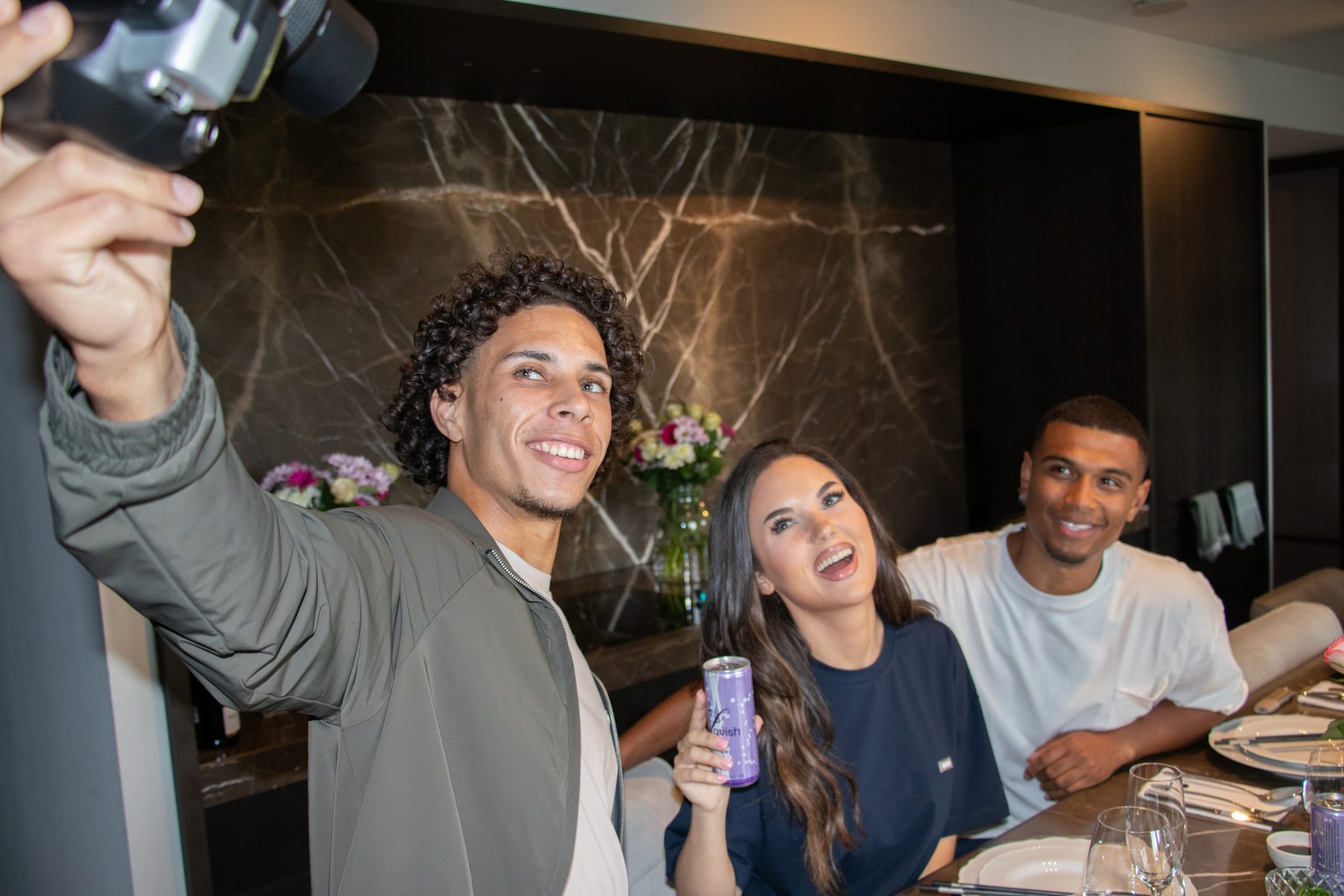 Friends taking a selfie with a camera around the dinner table