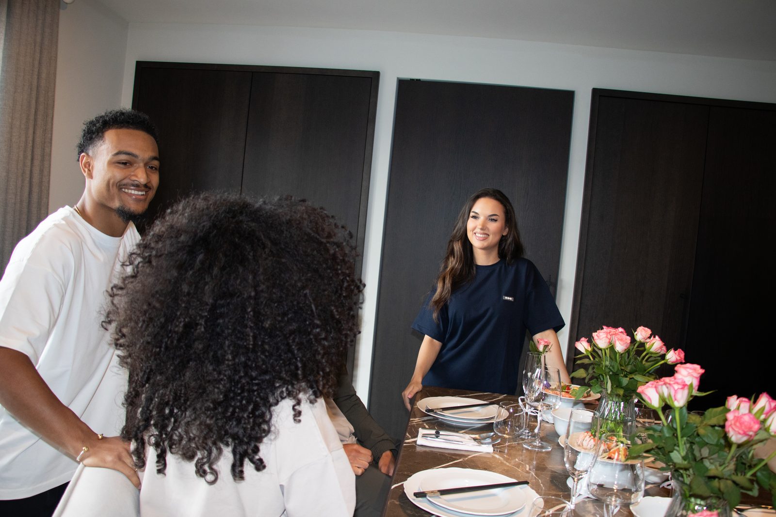 Friends talking around a table set with pink roses
