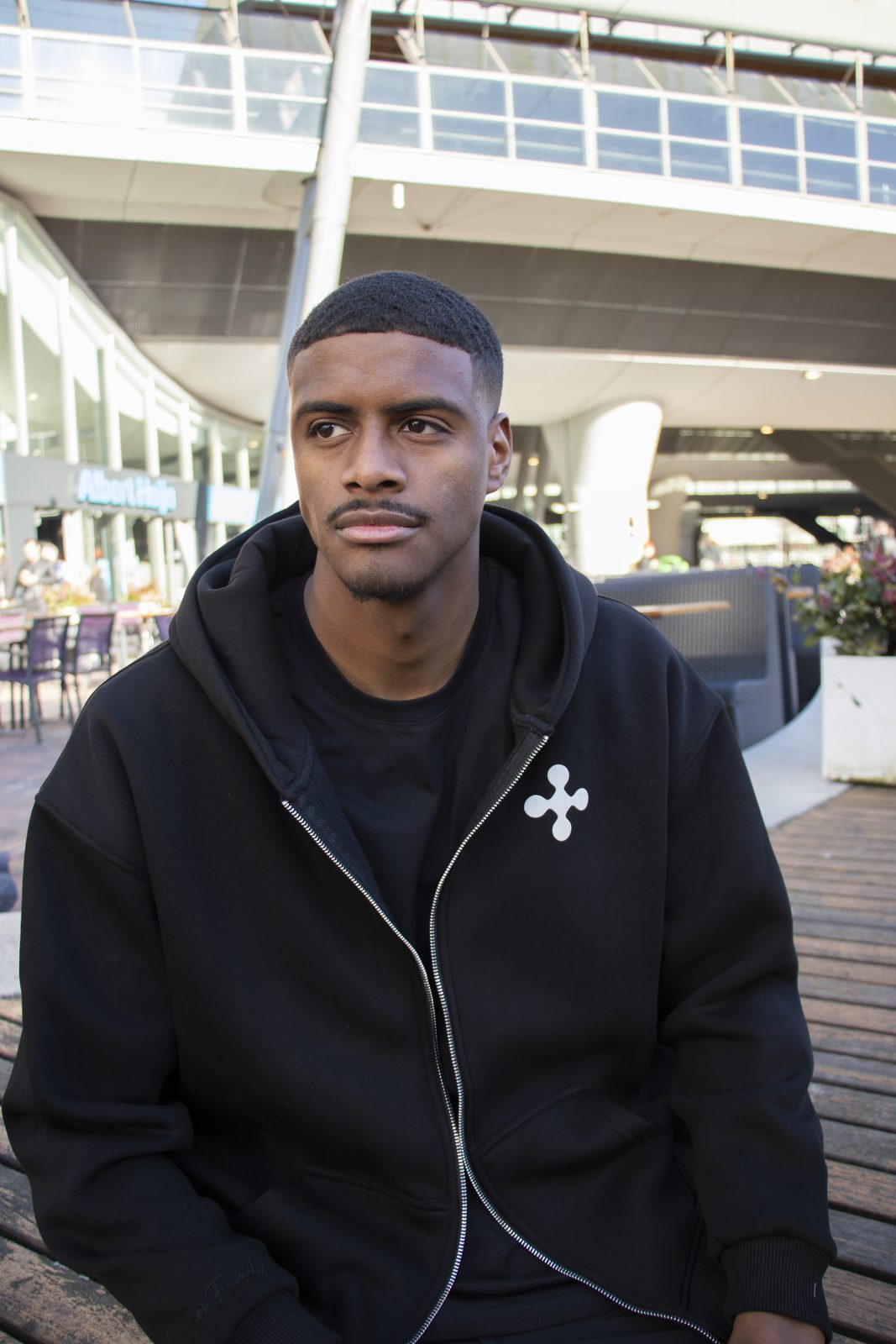 Model in a black LMF zip hoodie by the water