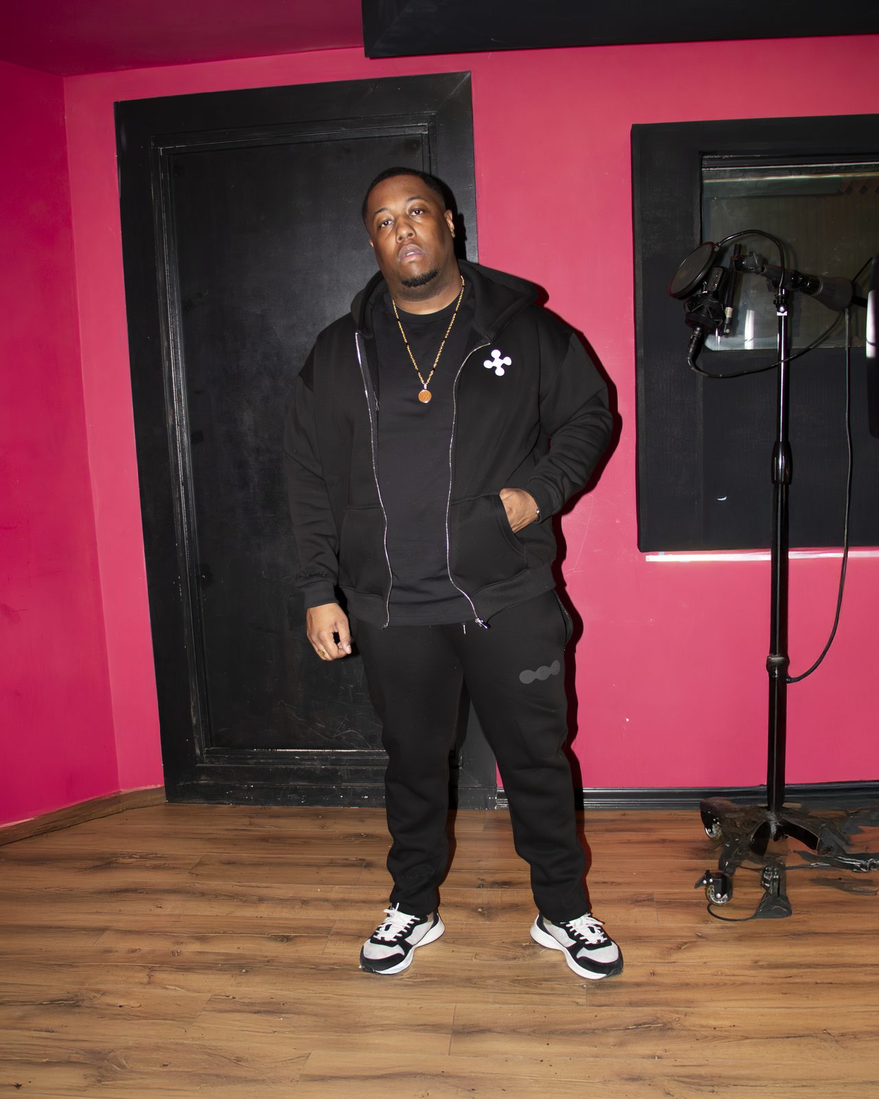 Model in a black LMF tracksuit against a pink wall