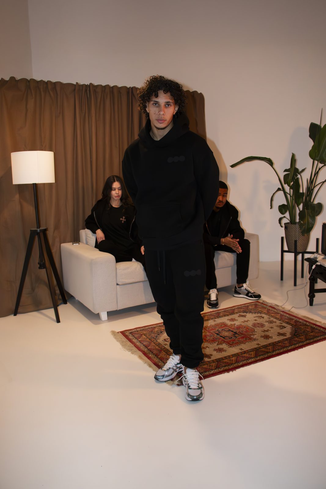 Model in a black LMF tracksuit walking across a rug