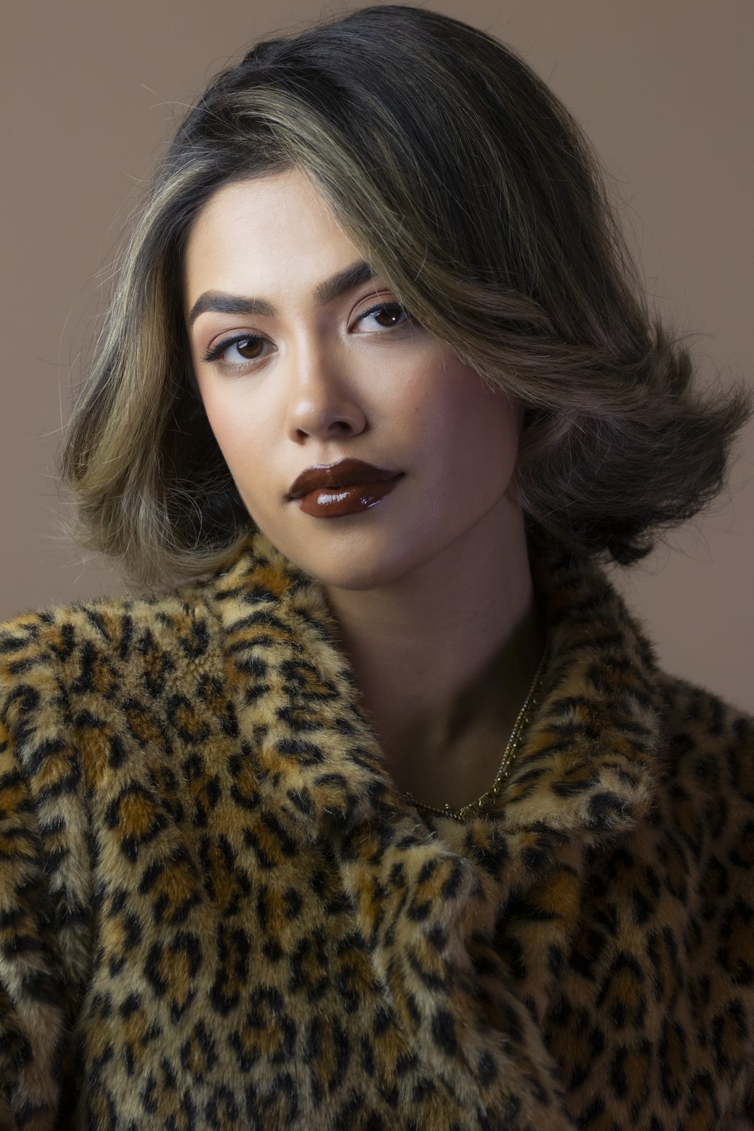 Portrait of a model in a leopard fur coat with brown lipstick