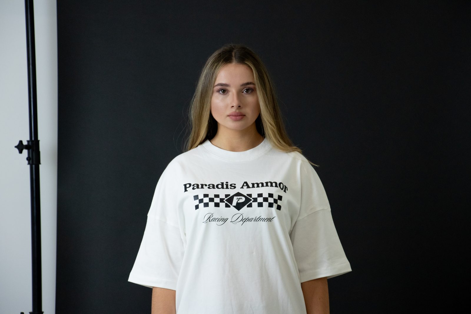 Model in a white Paradis Ammor Racing Department tee with chequered-flag print