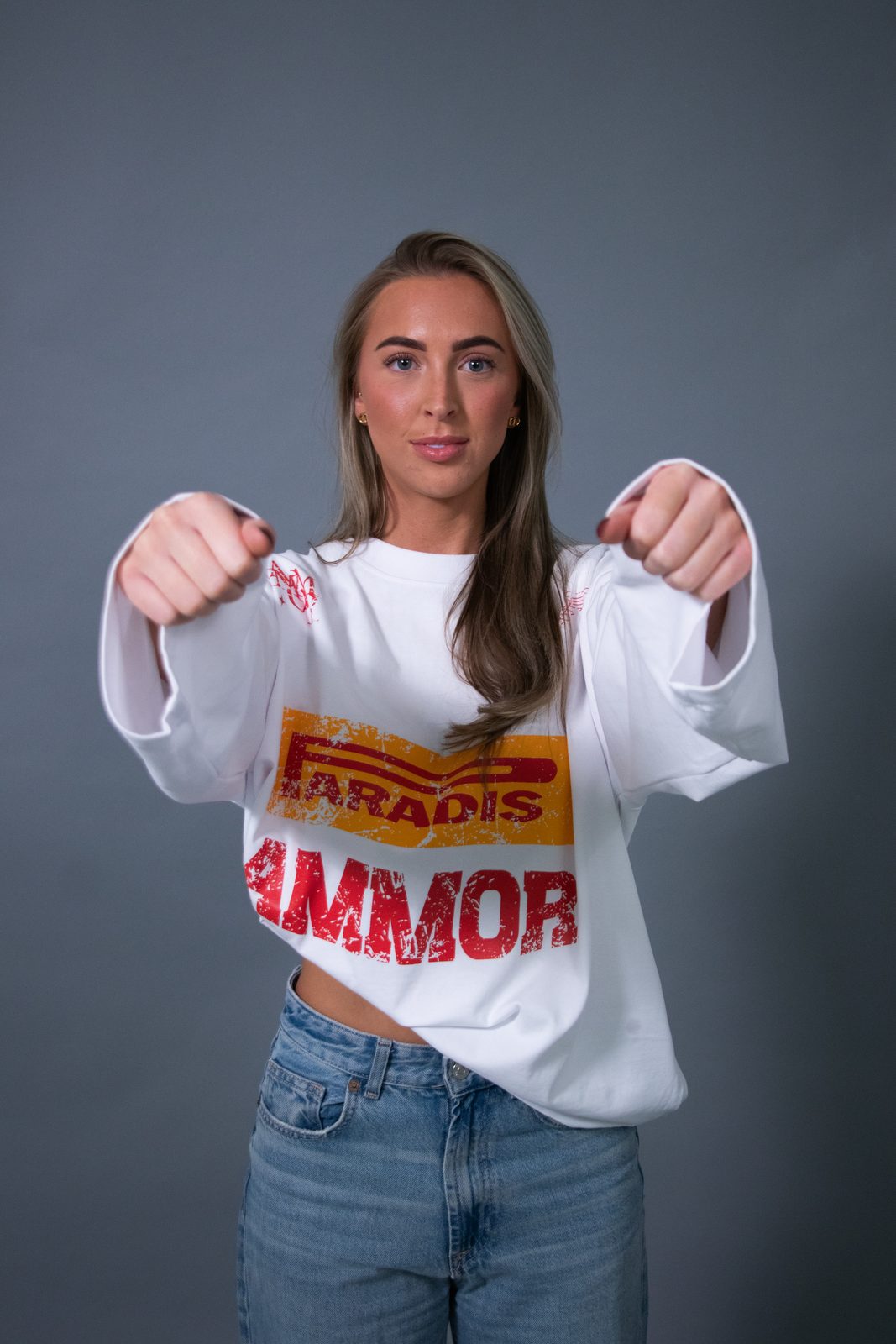 Model stretching a white racing longsleeve towards the camera