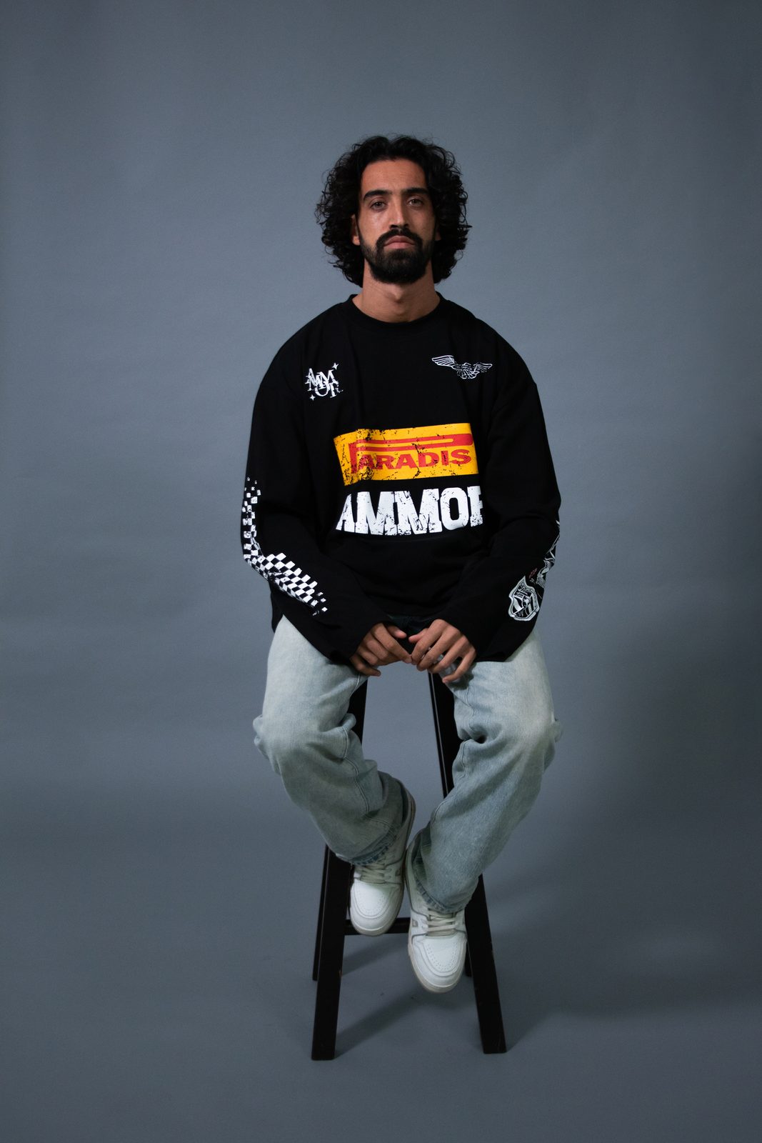 Model on a stool in a black Paradis Ammor racing longsleeve