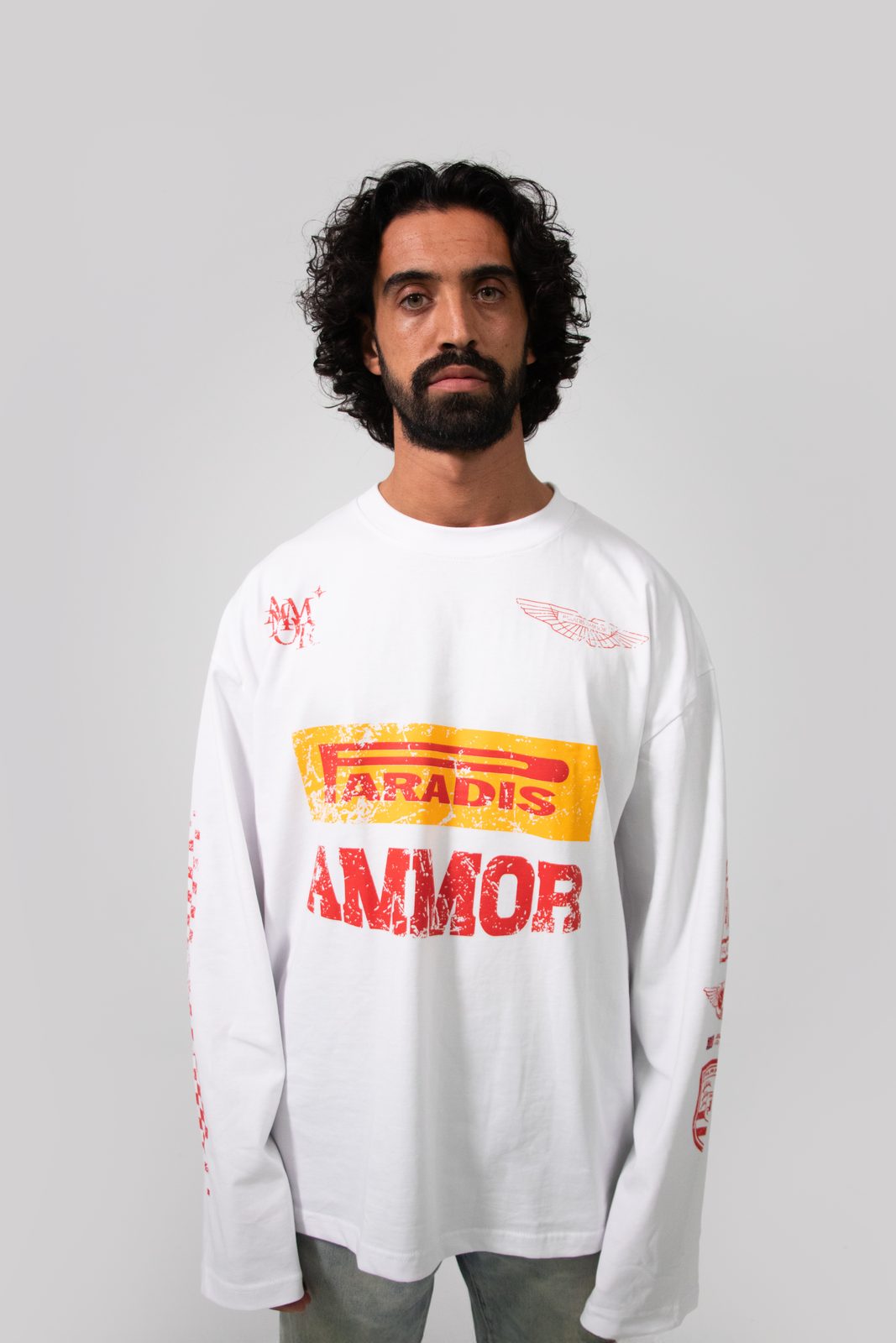 Model in a white Paradis Ammor racing longsleeve on a grey e-commerce backdrop