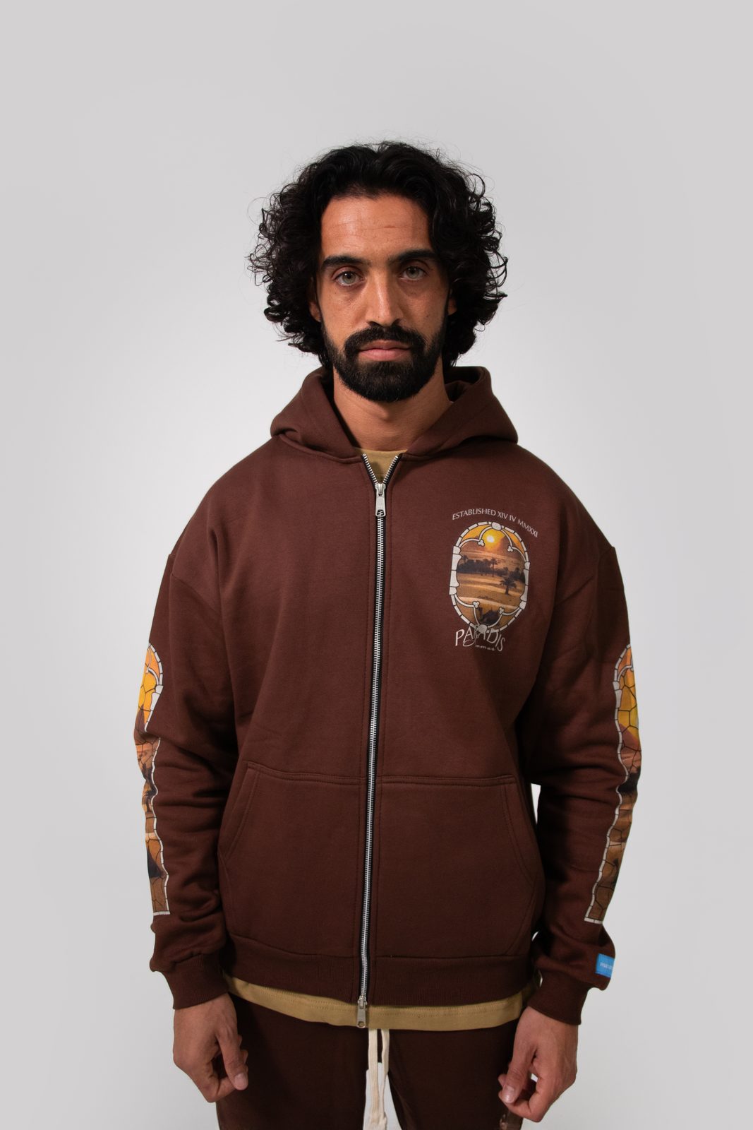 Model in a brown Paradis zip hoodie with printed sleeves