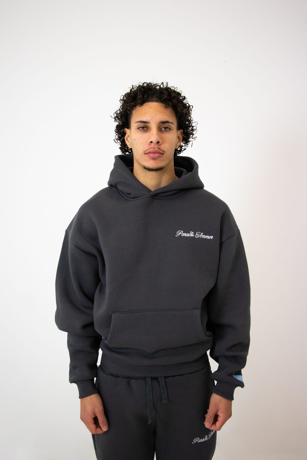 Model in a dark grey Paradis Ammor hoodie and joggers