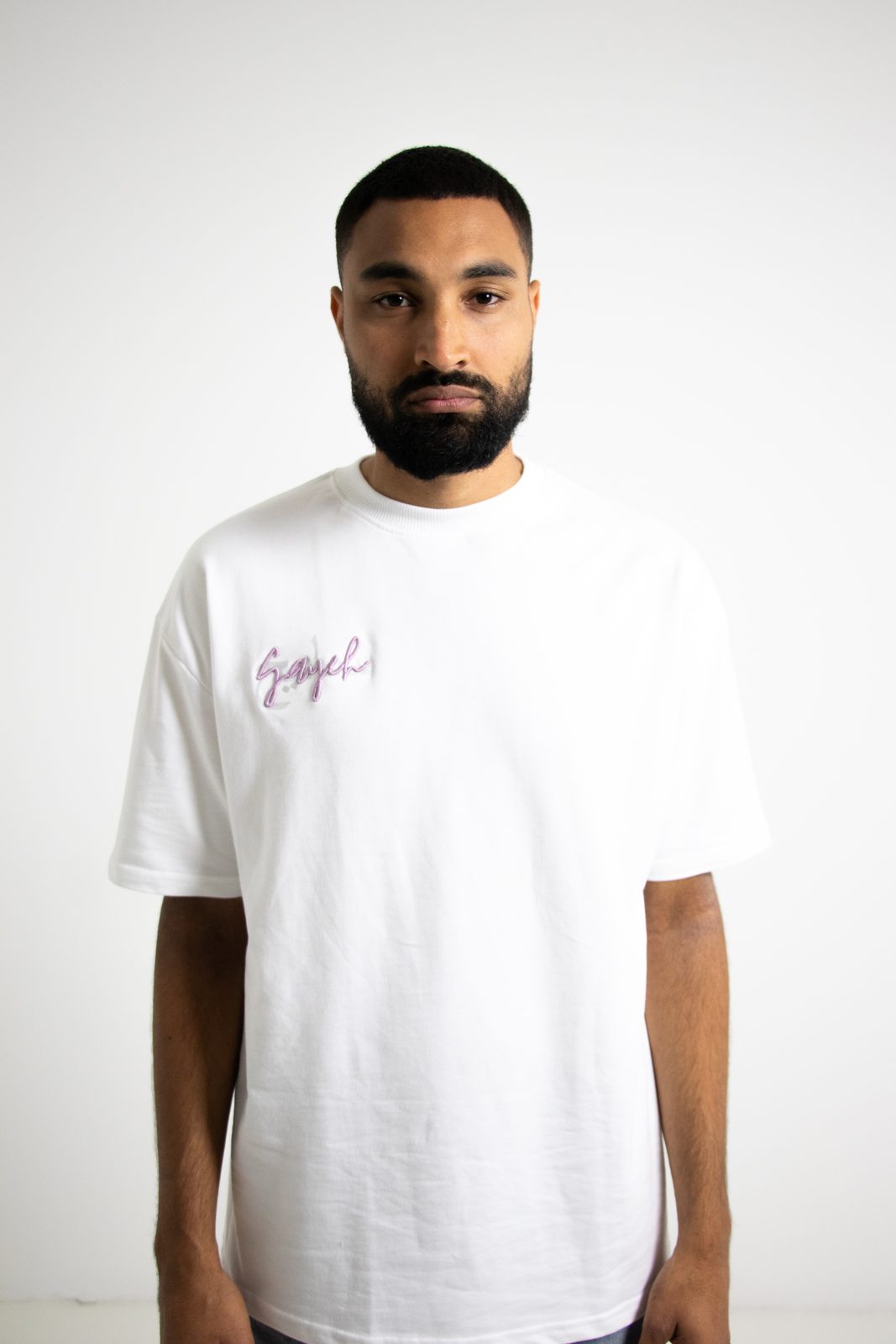 Model in a white SAYEH tee with a pink script logo