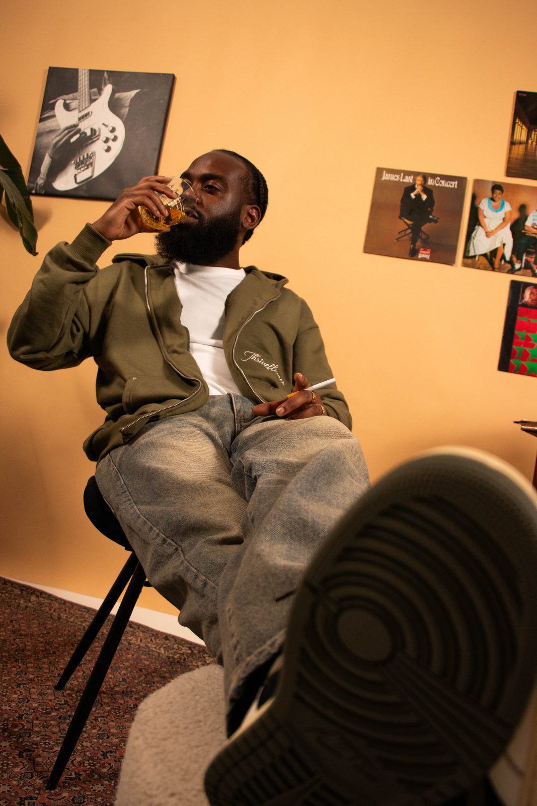 Model in an olive hoodie leaning back with his feet up