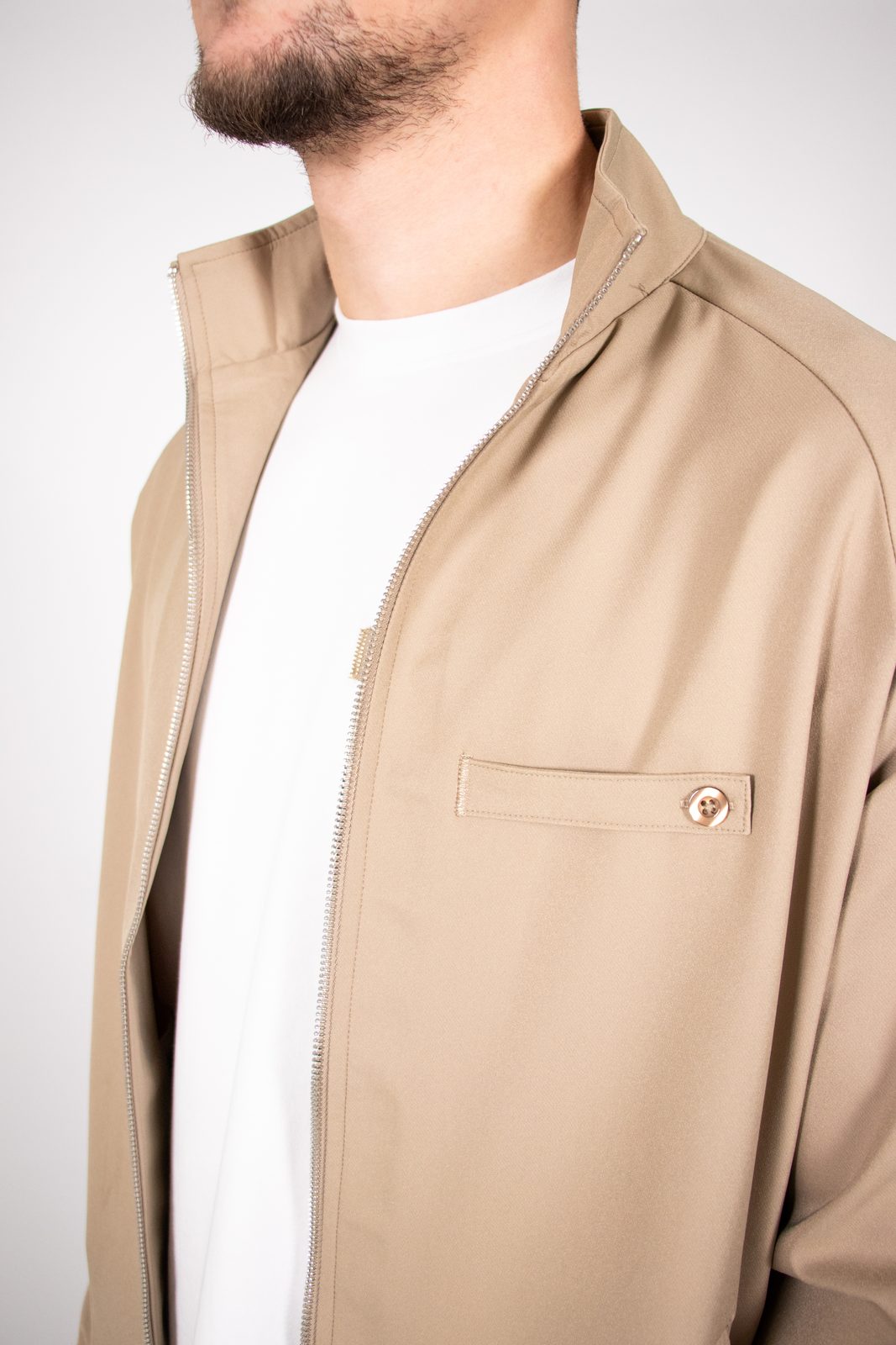 Close-up of a beige Thrivefluence jacket with pocket hardware