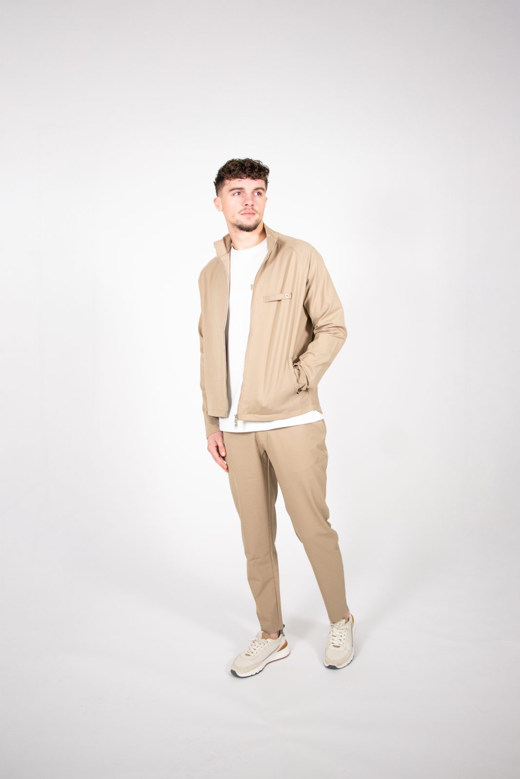 Model in a beige Thrivefluence suit on a white studio backdrop