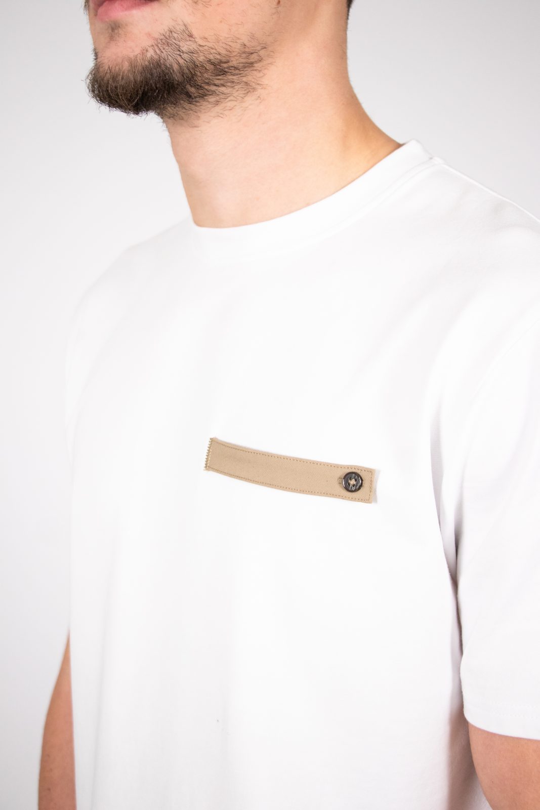 Close-up of a white tee with a beige pocket tab