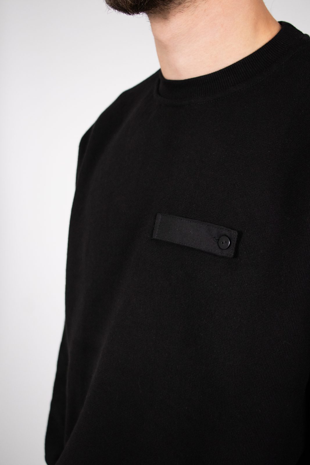 Close-up of a black sweater with a pocket tab