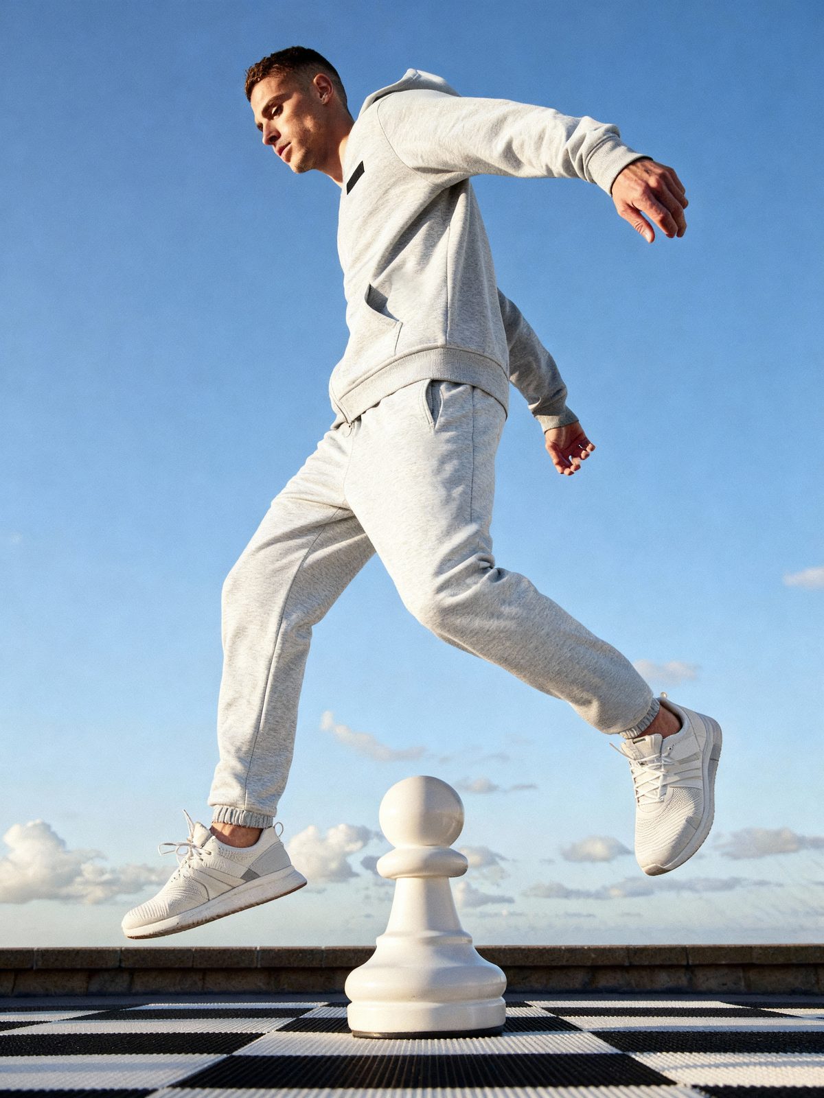 AI image: model in a grey tracksuit leaping over a giant pawn