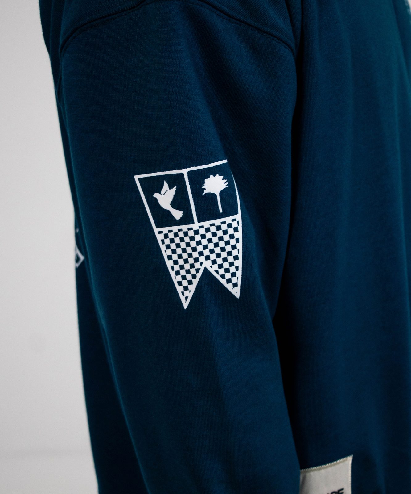 Close-up of an embroidered crest on a teal sleeve