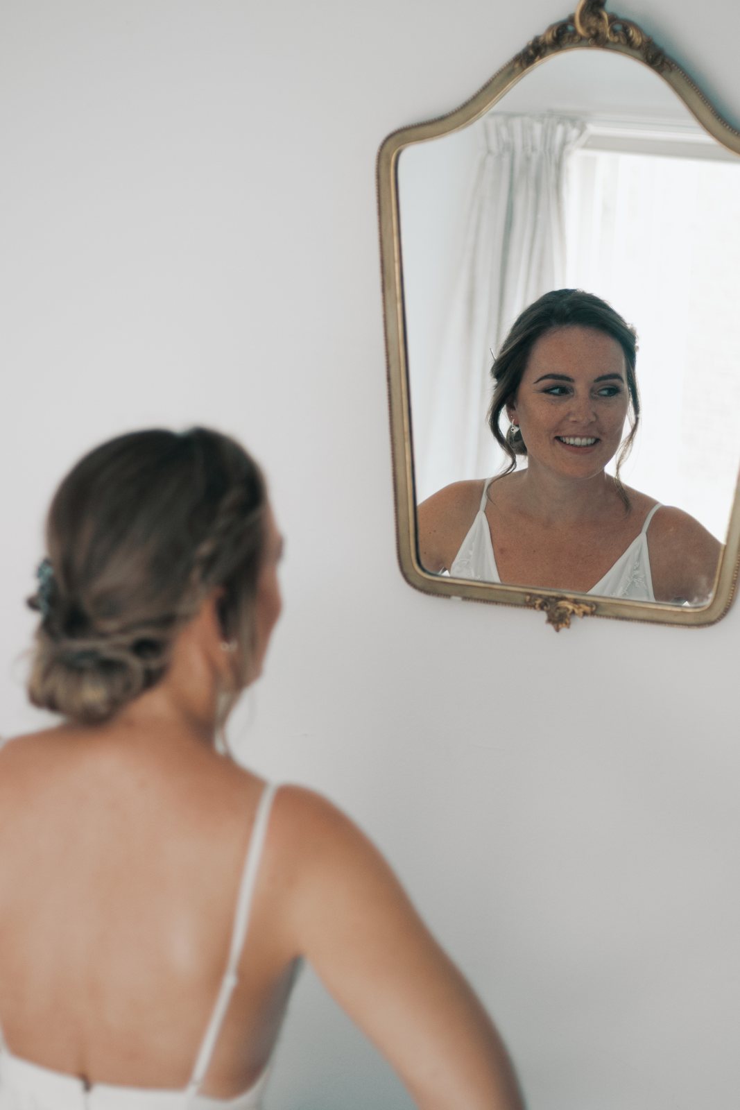 Imre smiling at herself in an antique gold mirror
