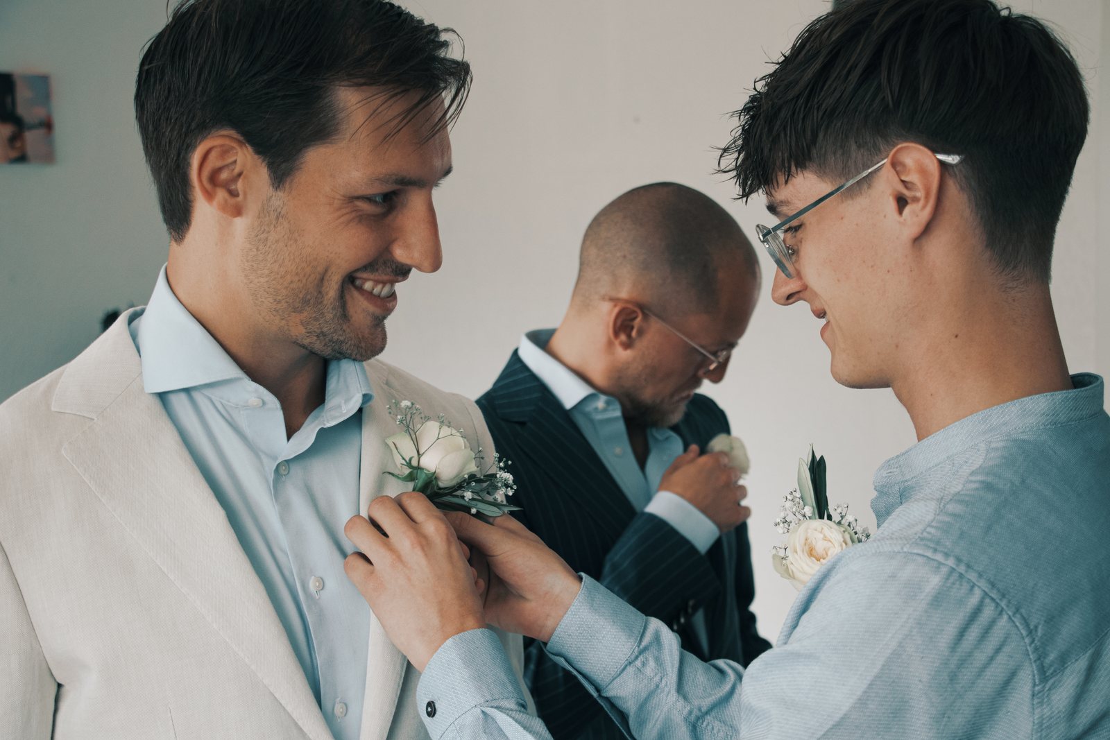 Chris laughing while friends pin on his boutonniere