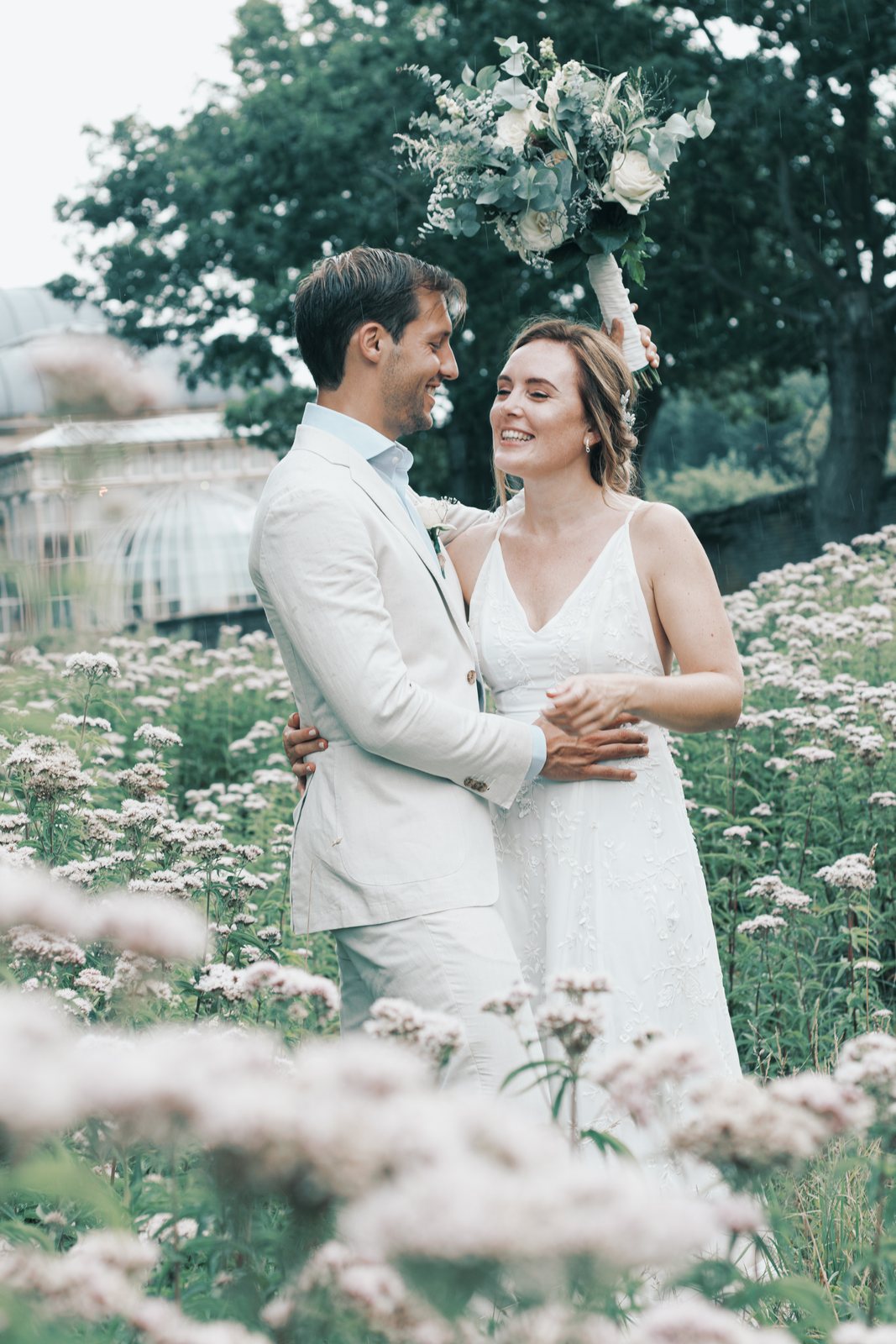 Imre and Chris laughing in a meadow of pale wildflowers
