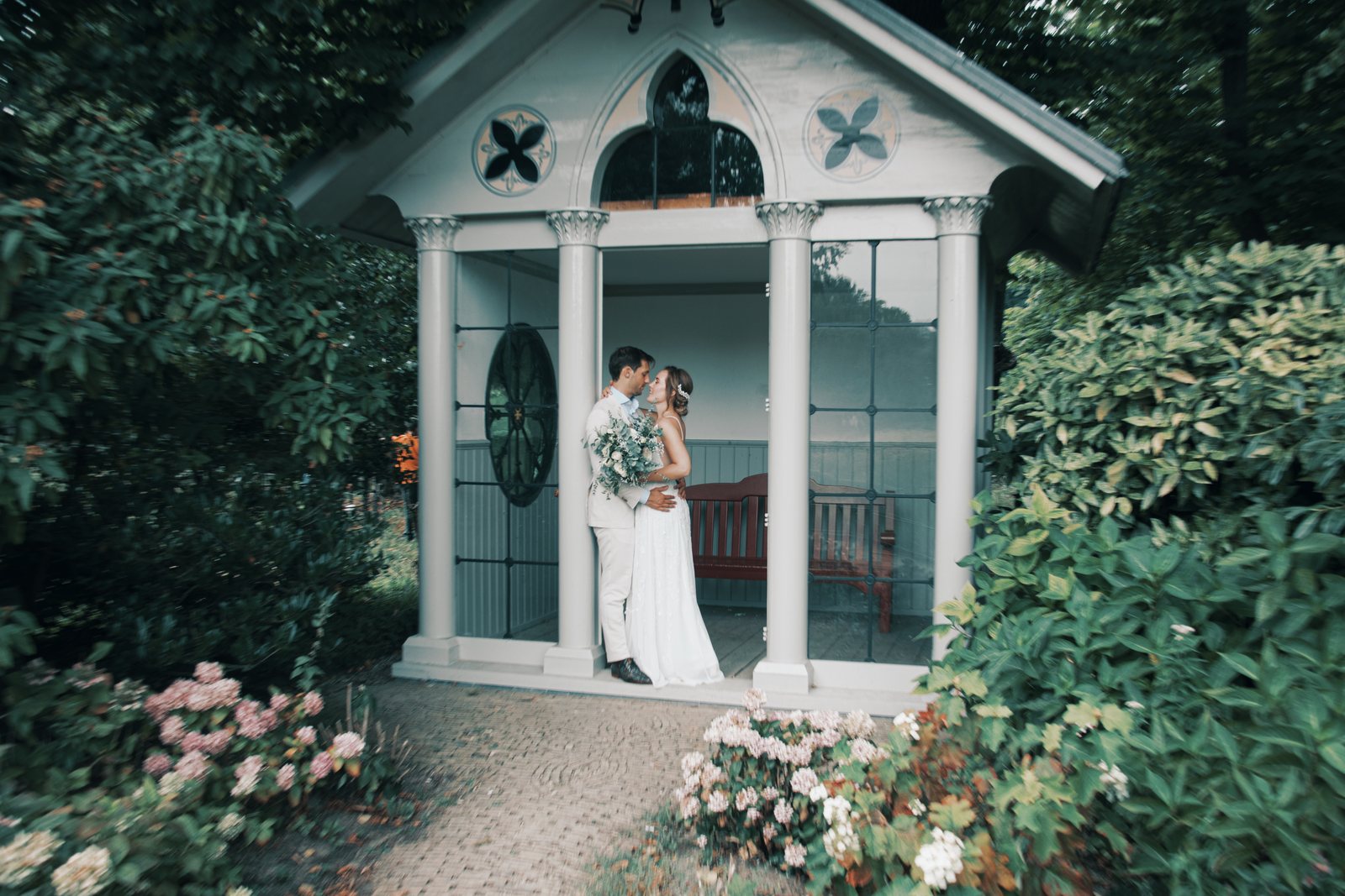 The couple kissing inside a small white garden pavilion