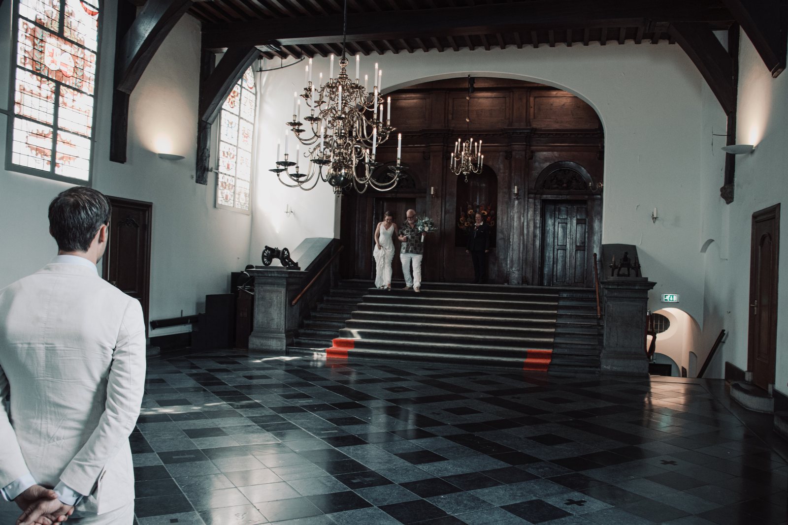 Chris waiting with his back to the camera in the grand hall of the town hall