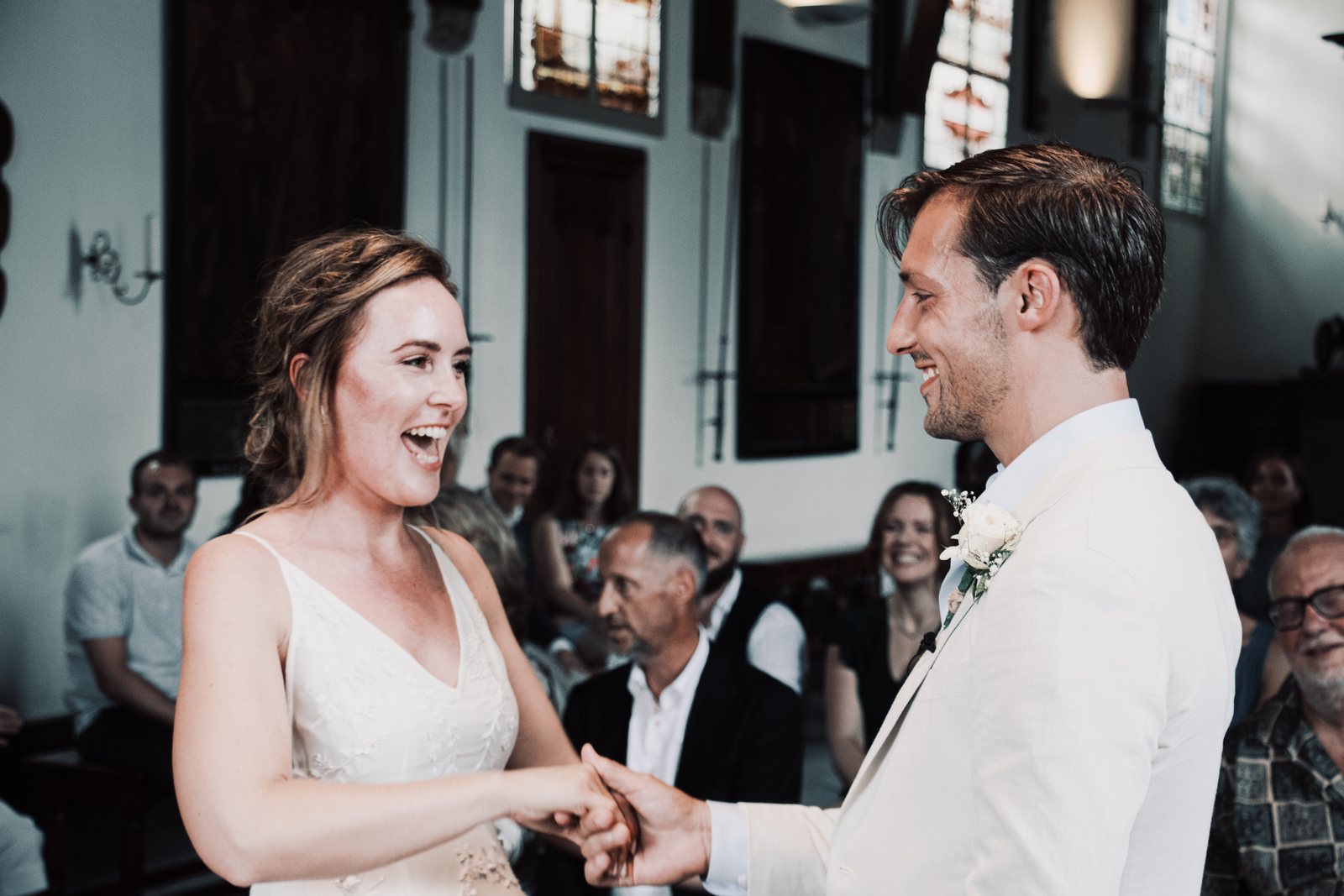 Imre laughing in surprise as Chris takes her hands during the vows