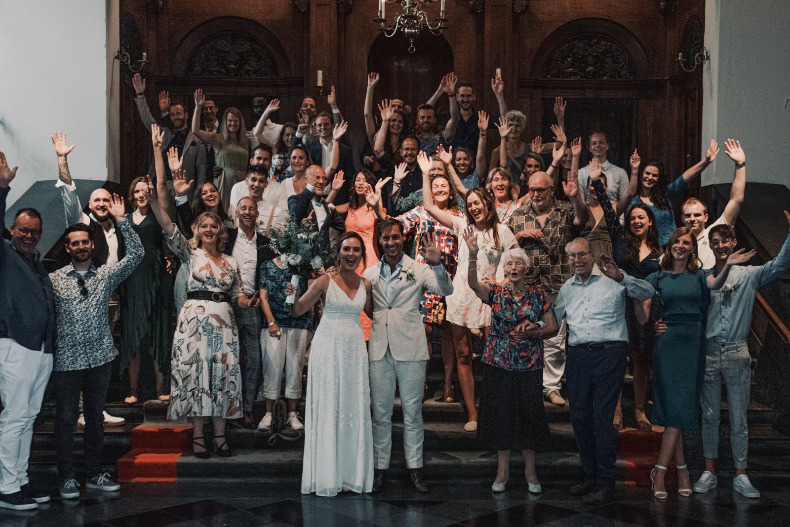 All the guests cheering with their arms raised on the town hall stairs
