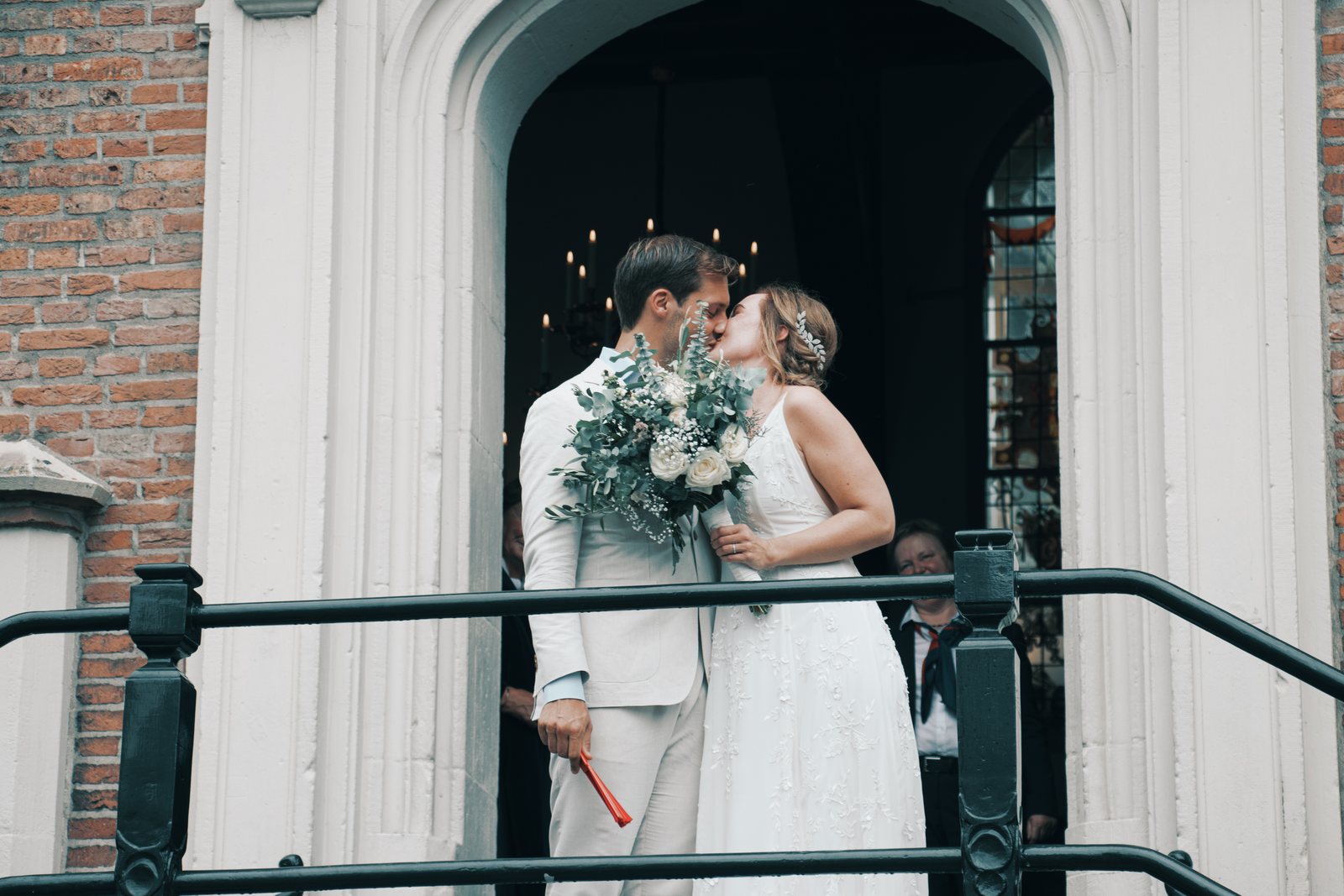 Imre and Chris kissing in the arched doorway of the town hall