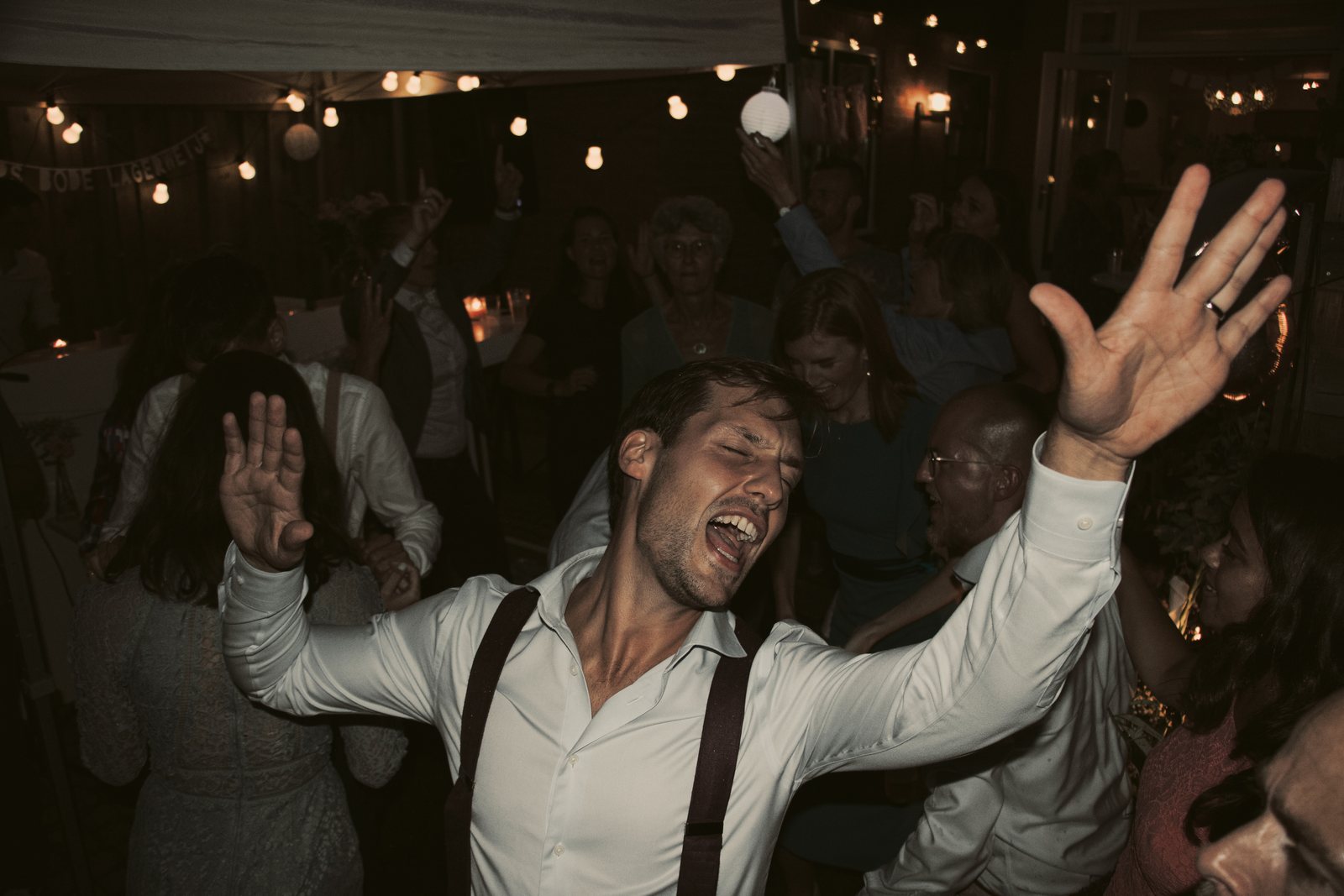 Chris with both arms in the air, singing on the crowded dance floor
