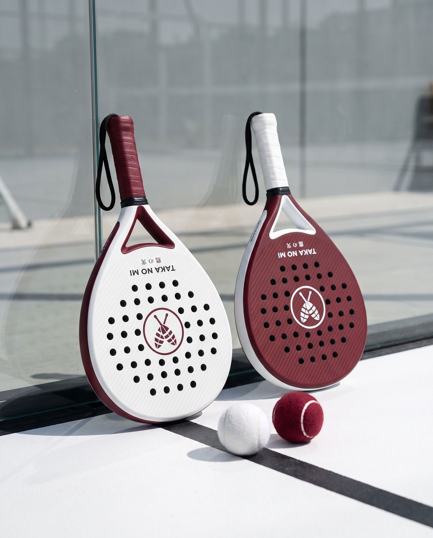 TAKA NO MI Shiro and Enji padel rackets standing beside matching balls on court